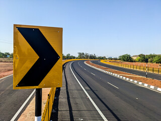 the indian empty road with yellow arrow and a slight curve with no vehicles