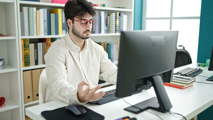 Young hispanic man student doing yoga exercise at library university