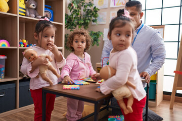 Hispanic man and girls having lesson at kindergarten