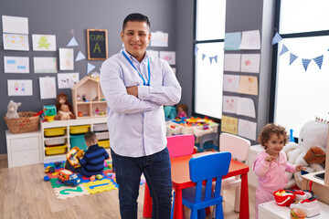 Hispanic man with boy and girl standing with arms crossed gesture at kindergarten