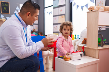 Hispanic man and girl playing supermarket game sitting on table at kindergarten