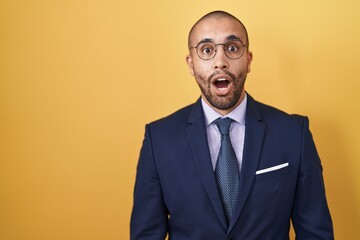 Hispanic man with beard wearing suit and tie afraid and shocked with surprise expression, fear and excited face.