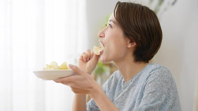 ポテトチップスを食べる若い女性　飲食イメージ