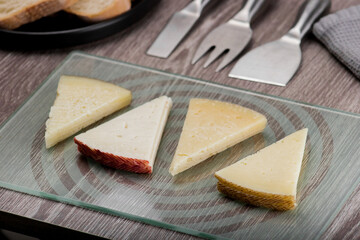 Pieces of manchego cheese stacked on a glass board