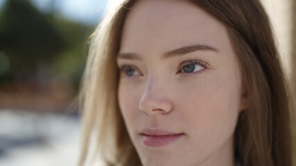 Young blonde woman looking to the side with serious expression at street