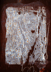 Traces on a rusty metal wall from a torn paper poster, glue residue on a rough surface, abstract...