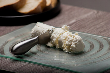 Sheep's cheese on glass board cut by a silver cutter