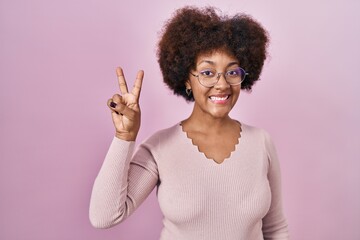 Young african american woman standing over pink background showing and pointing up with fingers number two while smiling confident and happy.