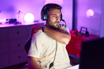 Young hispanic man streamer stressed using computer at gaming room