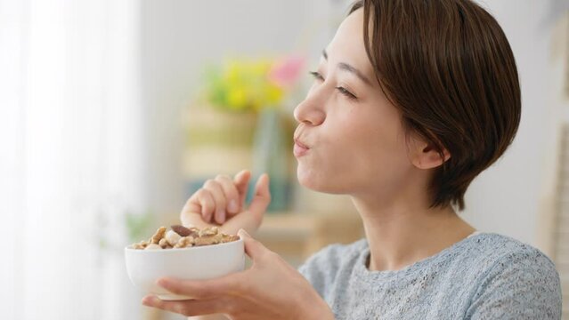 ミックスナッツを食べる若い女性　飲食イメージ	
