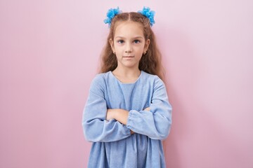 Young little girl standing over pink background skeptic and nervous, disapproving expression on face with crossed arms. negative person.