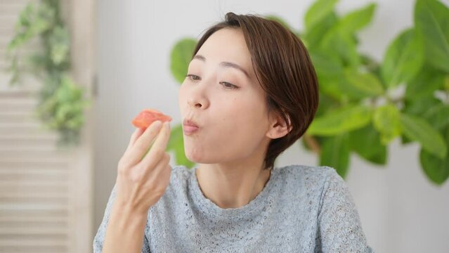 トマトを食べる若い女性　飲食イメージ	
