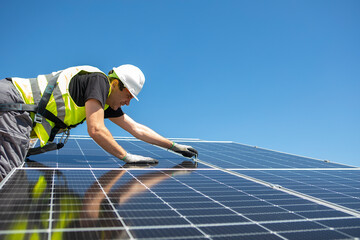 Man mounting modern solar batteries on house's roof. Environment friendly, green energy.