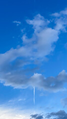 airplane contrails in the blue sky with clouds