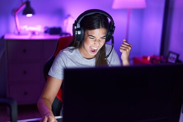 Young beautiful hispanic woman streamer playing video game with winner expression at gaming room © Krakenimages.com