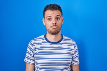 Obraz premium Young hispanic man standing over blue background depressed and worry for distress, crying angry and afraid. sad expression.