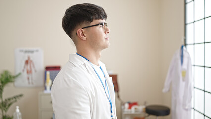 Young hispanic man doctor standing with serious expression at clinic