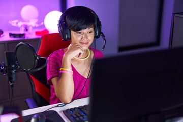 Middle age chinese woman streamer playing video game using computer at gaming room