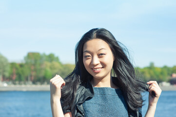 Beautiful young Asian woman with long black hair smiling at sunny day
