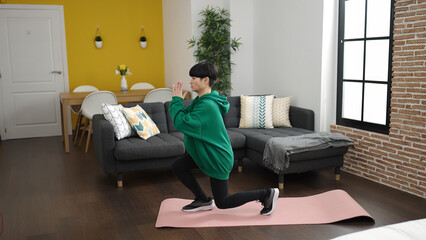 Young chinese woman training yoga exercise standing at home
