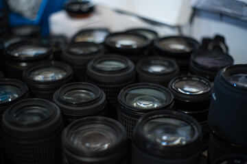 Close up shot of multiple camera lenses stacked on the table at flea market. 