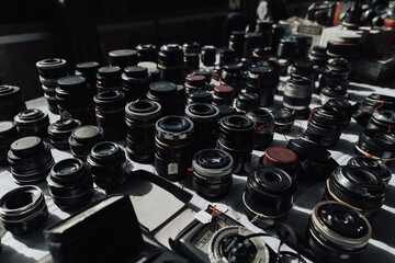 Multiple vintage photo camera lenses on the table at flea market. Photo equipment garage sale. - obrazy, fototapety, plakaty