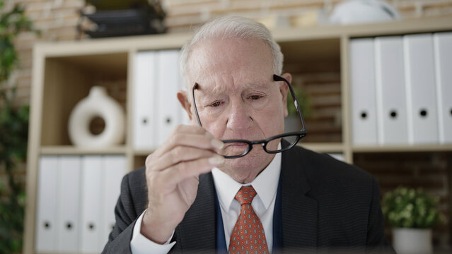 senior business worker holding glasses at office
