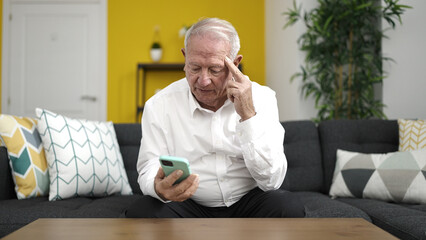 Fototapeta premium senior using smartphone with serious expression at home