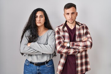 Young hispanic couple standing over white background skeptic and nervous, disapproving expression on face with crossed arms. negative person.