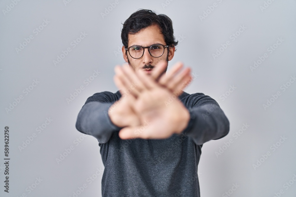 Sticker handsome latin man standing over isolated background rejection expression crossing arms and palms do