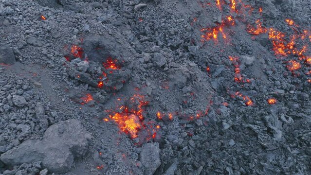 Aerial lava flow on Big Island in Hawaii, USA shot on drone. Volcano eruption on Mauna Loa mountain. Flowing lava and black rocks. Red hot molten lava flowing from crater through streams on slope