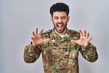 Arab man wearing camouflage army uniform smiling funny doing claw gesture as cat, aggressive and...