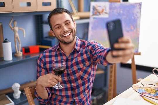 Young man artist make selfie by smartphone drinking wine at art studio