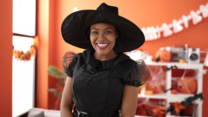 African american woman wearing witch costume having halloween party at home