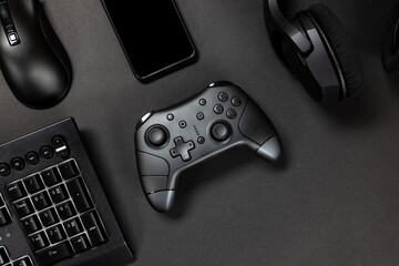 Top view of game controller with gadgets and mobile phone on black gamer desk