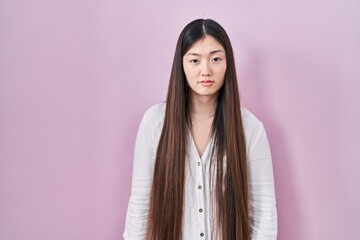 Fototapeta premium Chinese young woman standing over pink background looking sleepy and tired, exhausted for fatigue and hangover, lazy eyes in the morning.