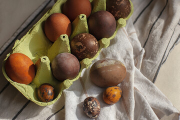 Easter multi-colored chicken and quail eggs, dyed with natural dyes in green cardboard packaging on...