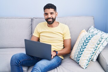Young arab man using laptop sitting on table at home