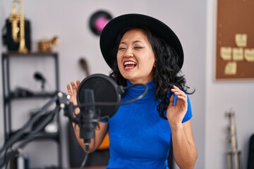 Young chinese woman artist singing song at music studio