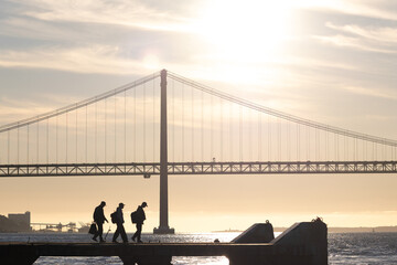 Skateboarders hang out on the waterfront at early sunset - suspension bridge on the background