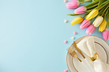 Happy Mother's Day concept. Top view photo of plate cutlery knife fork and napkin with gold ring bunch of colorful tulips and small hearts baubles on isolated pastel blue background with copyspace