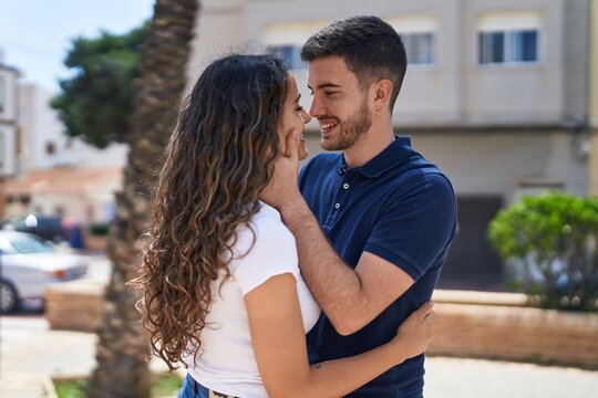 Young hispanic couple smiling confident hugging each other and kissing at park