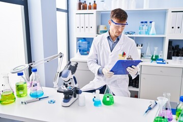 Young man scientist reading report at laboratory