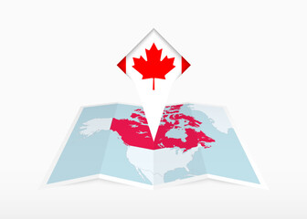 Obraz premium Canada is depicted on a folded paper map and pinned location marker with flag of Canada.