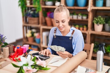 Young blonde woman florist smiling confident counting dollars at florist