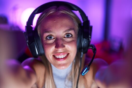 Young blonde woman streamer smiling confident make selfie by camera at gaming room