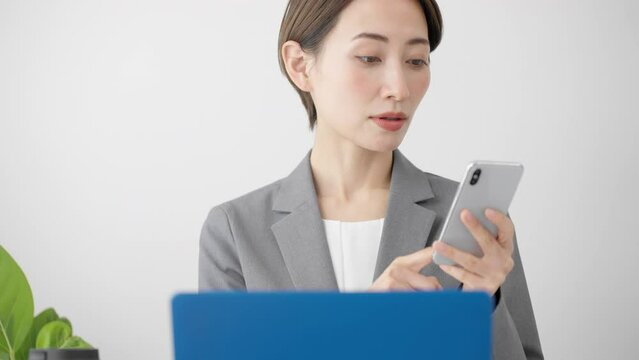 ノートパソコンとスマートフォンを使う若い女性　ビジネスイメージ	

