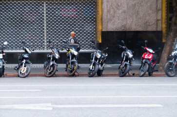 Lots of motorcycles on the street of Buenos Aires. Outdoor parking for bicycles. The photo is out of focus.