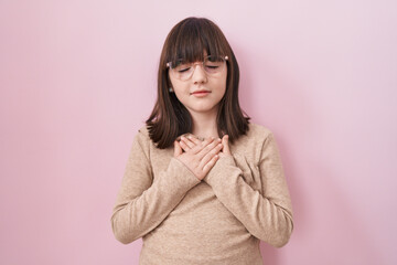 Little hispanic girl wearing glasses smiling with hands on chest with closed eyes and grateful gesture on face. health concept.