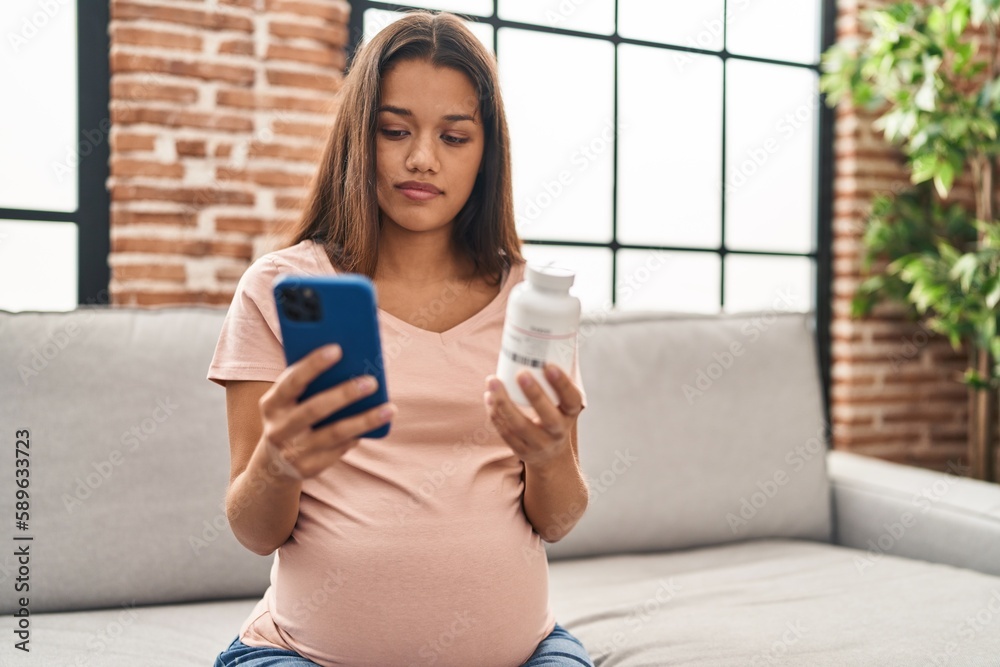 Sticker young latin woman pregnant using smartphone holding bottle of pills at home